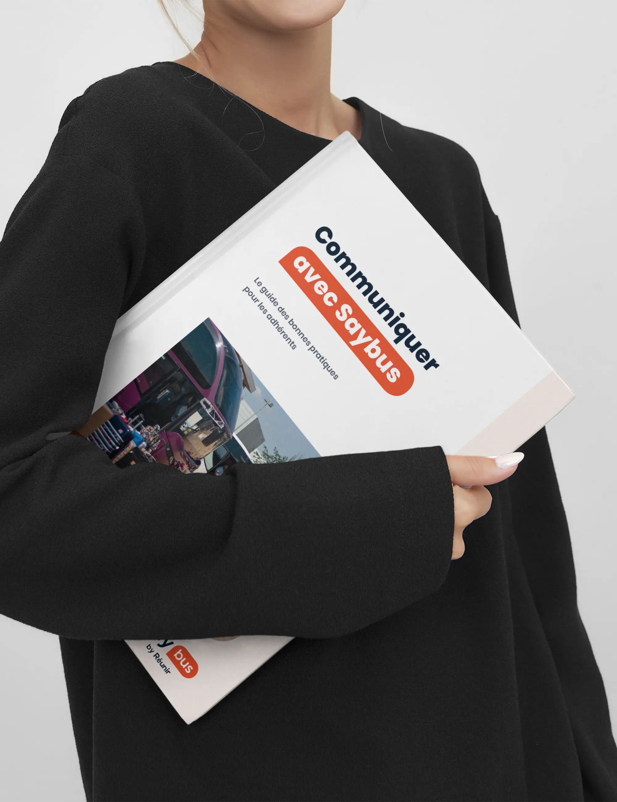 Femme tenant une brochure "Communiquer avec Saybus" dans ses bras